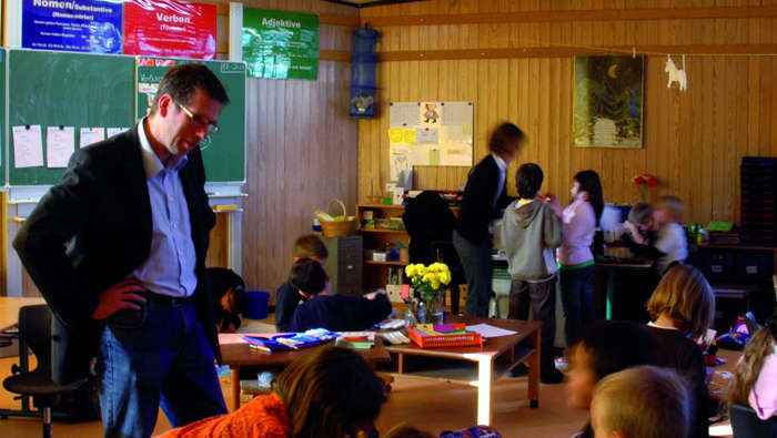 A teacher helps students at In der Alten Forst, illuminated by Philips school lighting