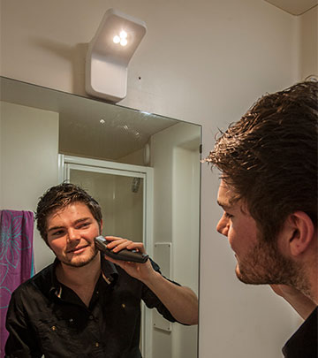 Guy shaving his beard in front of the mirror