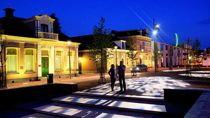 Man and woman are walking in a square beautified with Philips lighting