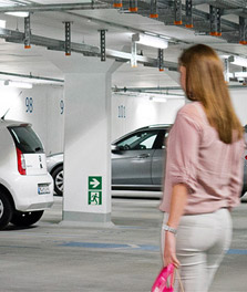 Woman walks to parked car in bright and sustainable green parking garage