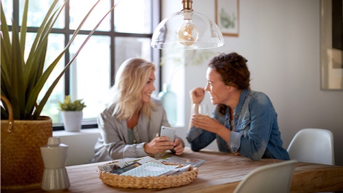 Two women at home talking underneath a Philips light bulb