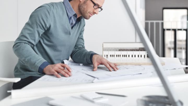 a man working at home at a cluttered desk