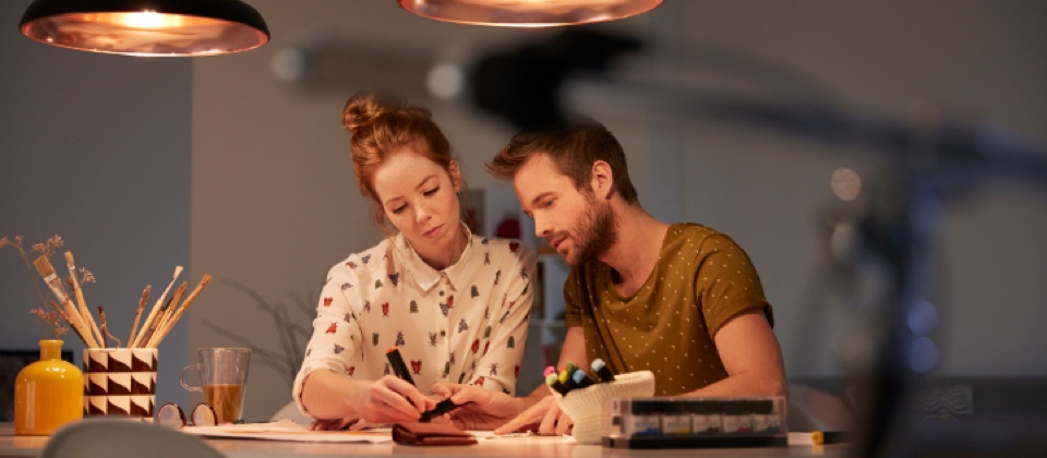 Two people sitting at a table under task lighting