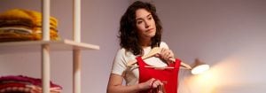 "Warm LED desk lamp illuminates woman selecting clothes, showcasing energy-efficient task lighting for personal styling in home closet space."
