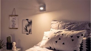 "Stylish bedroom with adjustable LED spotlight creating cosy ambiance, illuminating geometric bedding and minimalist decor."