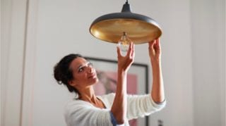 Woman screwing in a consumer lightbulb at home